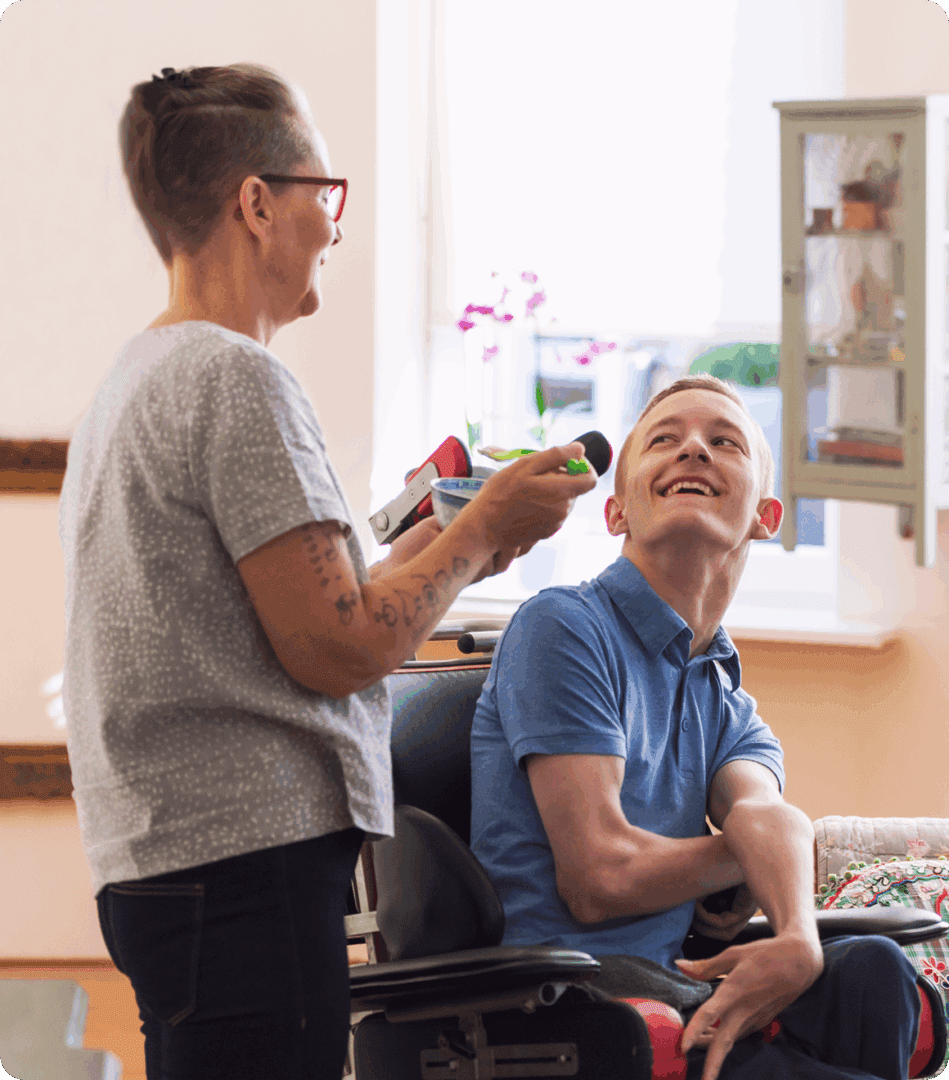 Woman assisting man in a wheelchair, smiling.