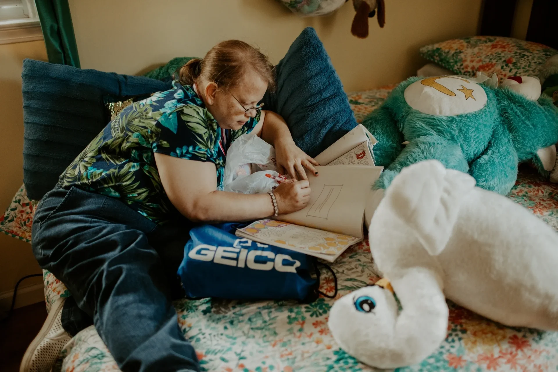 Person drawing on bed with plush toys.